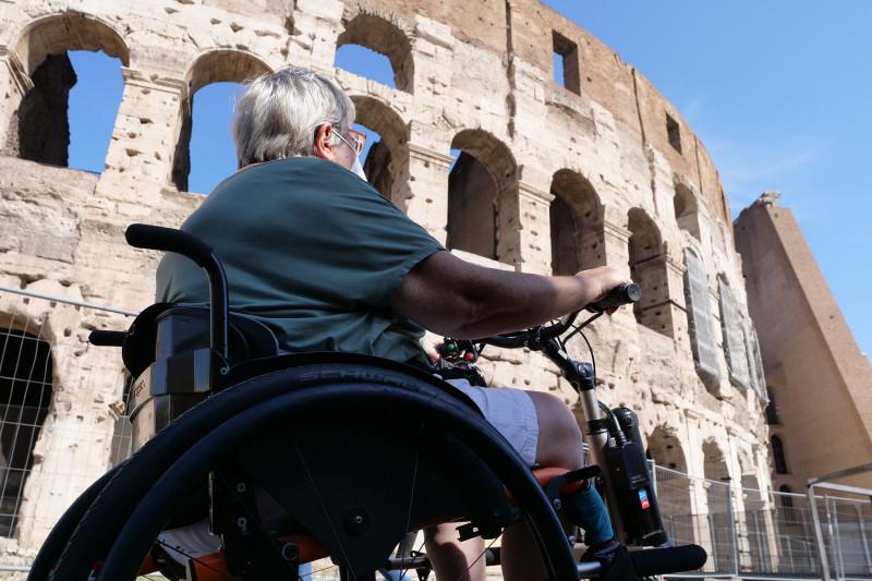 A person in a wheelchair inside the arena of the Colosseum.