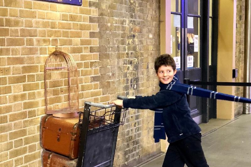 A tourist poses for a photo at the barrier at Platform 9 ¾.