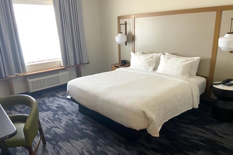 An accessible guest room with a carpeted floor, king-sized bed, bedside tables and a desk.