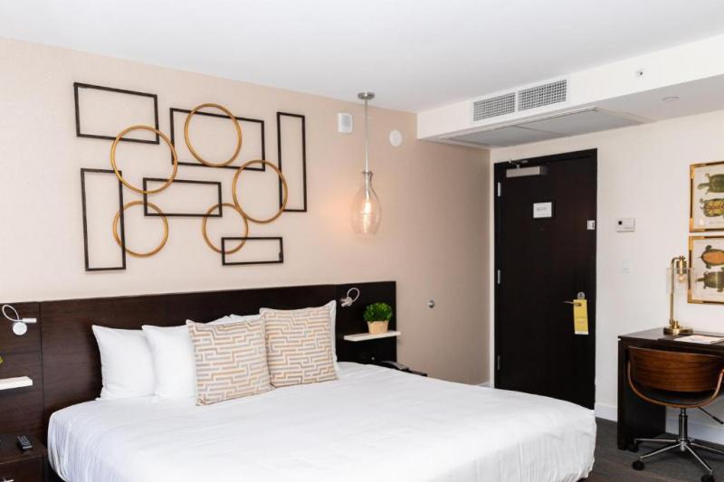 An accessible guest room with a king bed, a carpeted floor, a bedside table and a desk.