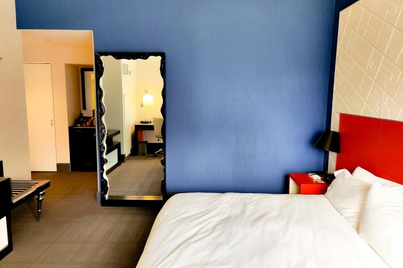 Guestroom with colorful decor and full-length mirror