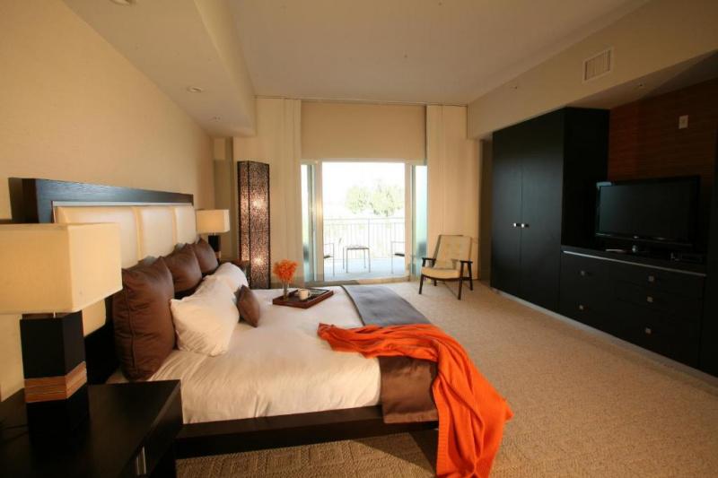 The king studio suite has a king-sized bed, nightstands, an armchair, closet, a large TV and a furnished balcony.
