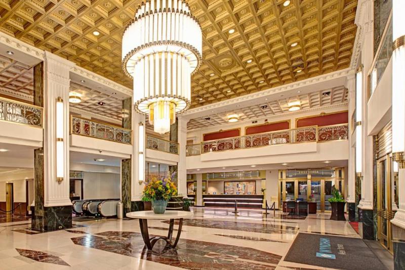 The hotel lobby has corniced ceilings, pillars, a feature chandelier and a marble floor.