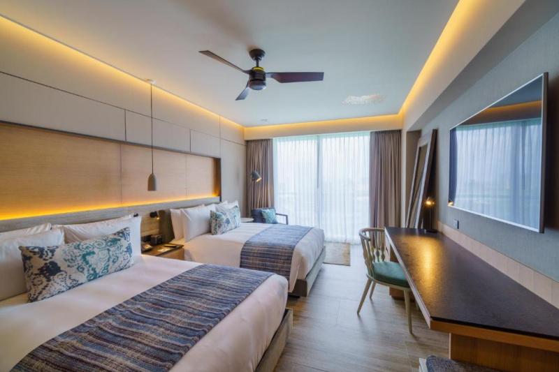The spacious room has 2 queen-sized beds with a central nightstand. Opposite the beds is a workstation and and movable chair. Floor space is limited.