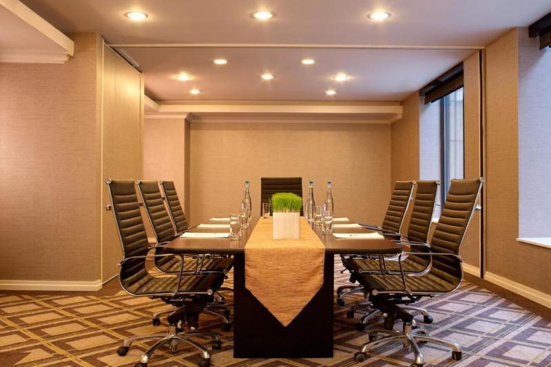 The carpeted meeting room has a table with 7 movable chairs in the center of the room.
