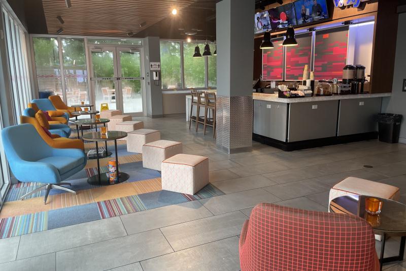 The WXYZ bar has a high counter lined with bar stools and a lowered section. There is a row of plush swivel chairs, tables and pouffes and a wide aisle leading to glass doors that provide step-free access to an outdoor seating area.