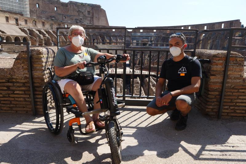 Woman on wheelchair and Wheel the World staff pose infront of Colosseum ruins