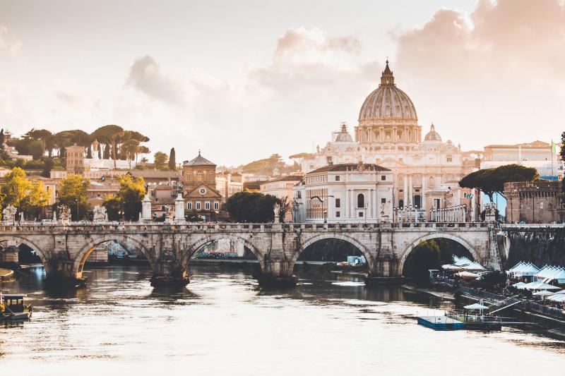 A view of Rome's skyline, with the Dome of Saint Peter's Cathedral and a bridge across the River Tiber.