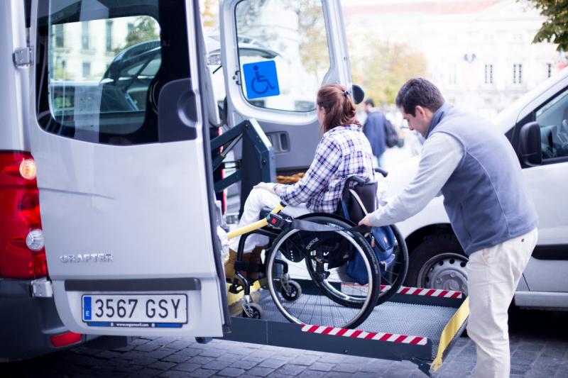 A wheelchair user being assisted to board an accessible van