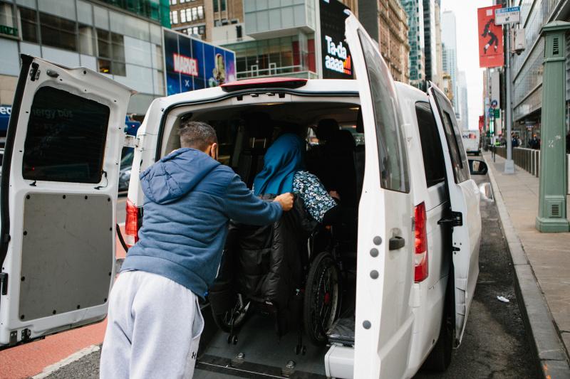 A wheelchair user being assisted aboard an accessible van