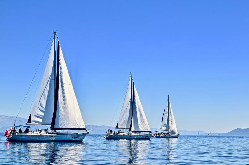 Three sailboats on calm water off the Scottish coast.