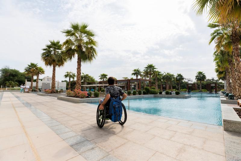A guest uses a wheelchair to explore the poolside outdooor space