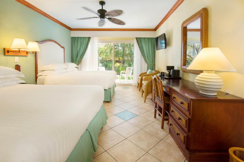 Two queen size beds side by side in a tiled room that opens to a private patio.
