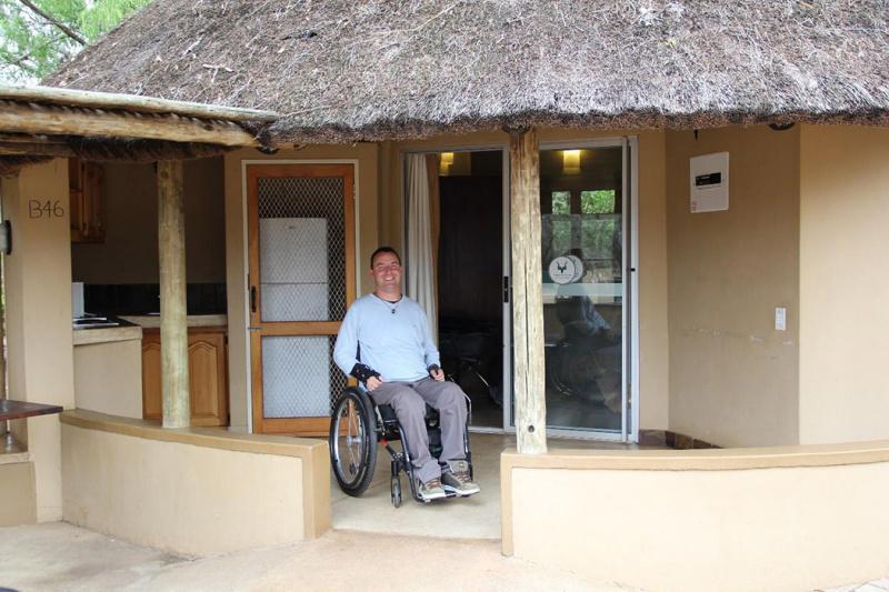 A guest relaxes in their wheelchair in the bungalow's front patio.