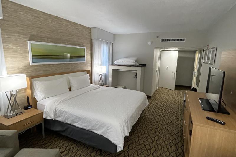An accessible guest room with a large double bed, a carpeted floor and a TV.