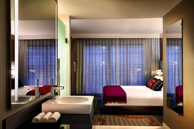 The bedroom of an accessible guest suite, with a king-sized bed, carpeted floors and large windows.
