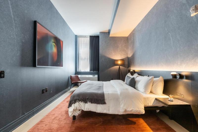 The accessible guest room, with a large bed, a rug, a chair and a wall-mounted flat-screen TV.