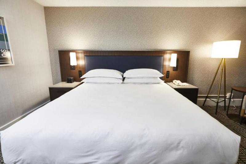 An accessible guest room with a double bed, a carpeted floor and a bedside telephone.