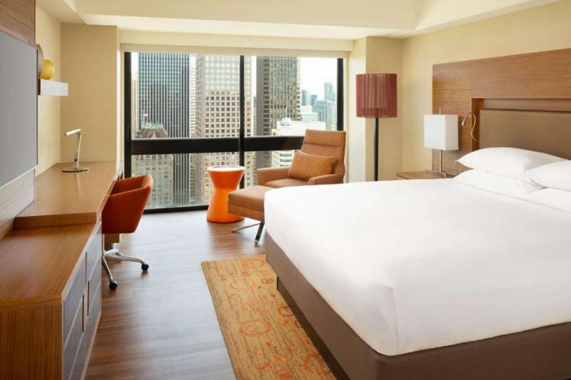 Guestroom with modern decor, wooden flooring and city views.