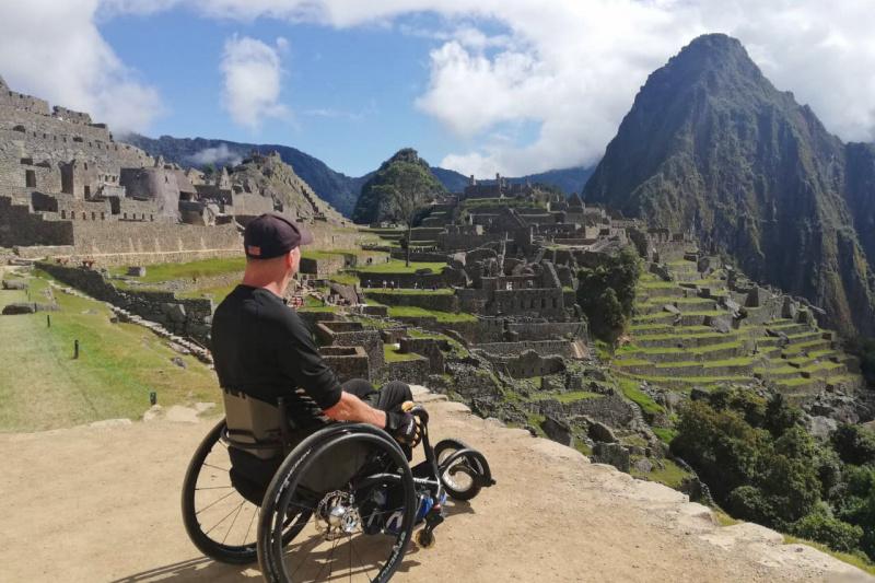 A man in a wheelchair admires the ancient Inca constructions of Machu Picchu.