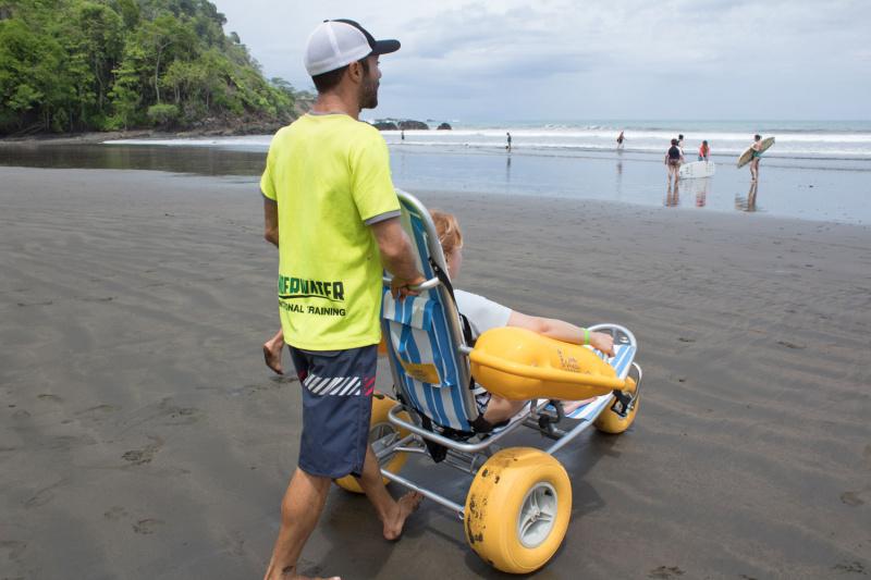 A traveler uses the amphibious wheelchair to traverse the beach and head to the water