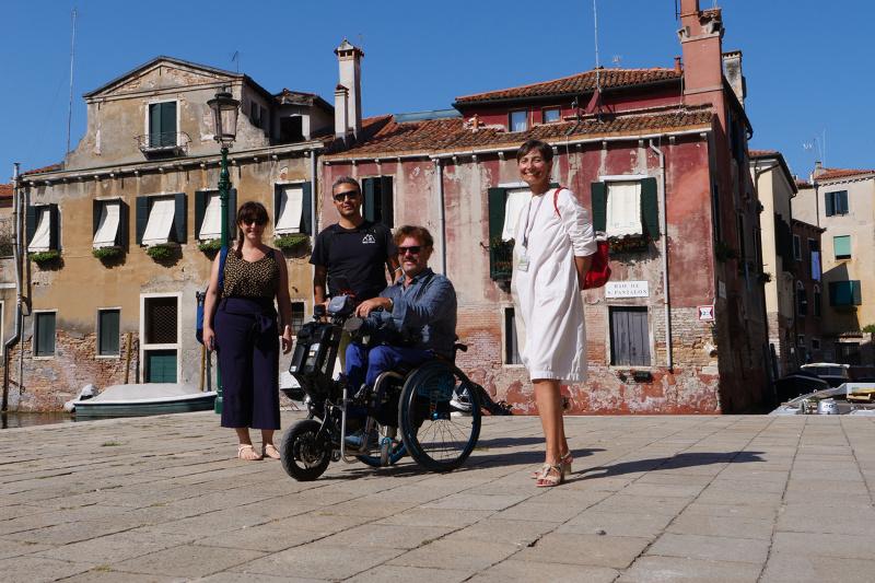 Tour participants and guide navigate Campo San Rocco's cobblestone streets and canals using wheelchair and other mobility related devices