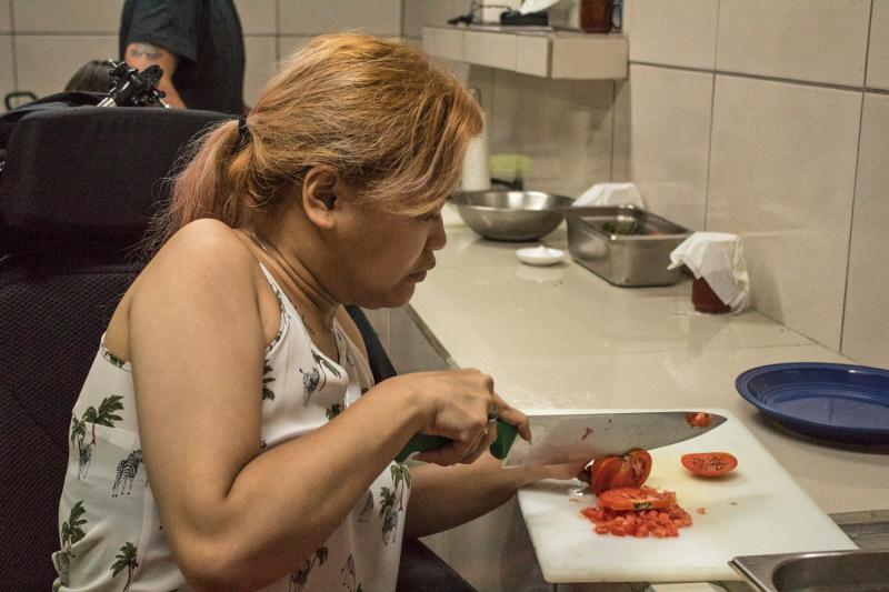 Guest and wheelchair user cuts tomatoes during cooking class