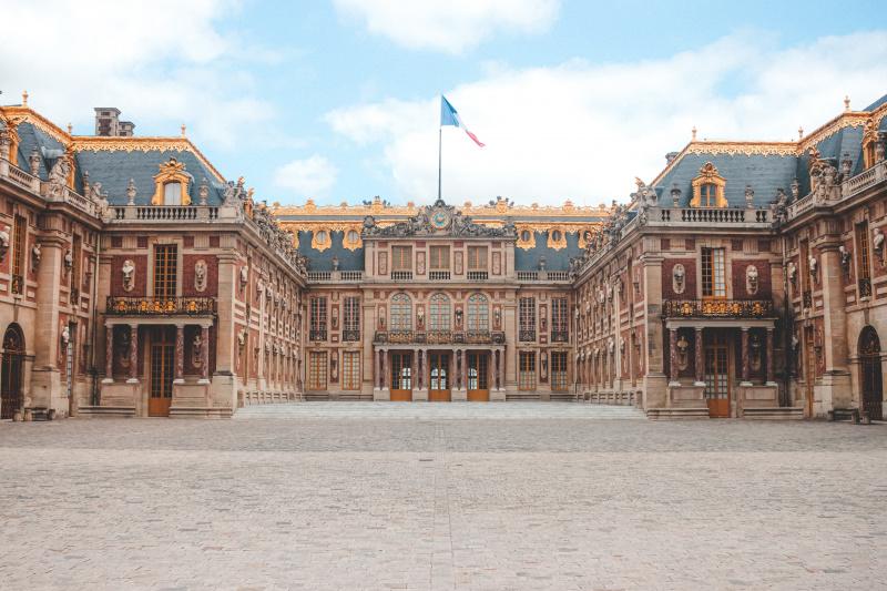The Palace of Versailles, set around a central courtyard covered with smooth cobblestones.